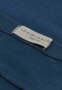 Marinblå bomullsplagg med en mjuk textur, som har en etikett med texten "intimissimi Natural" sydd på tyget.