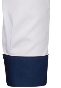 Giacca da chef con corpo bianco e polsini blu navy. Il materiale è liscio con una vestibilità su misura, garantendo un aspetto professionale.