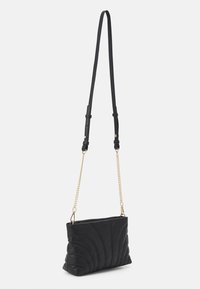 Borsa a tracolla in pelle nera con motivo a onde trapuntato. Caratterizzata da una tracolla in catena e pelle e una chiusura con zip. Forma compatta e rettangolare.