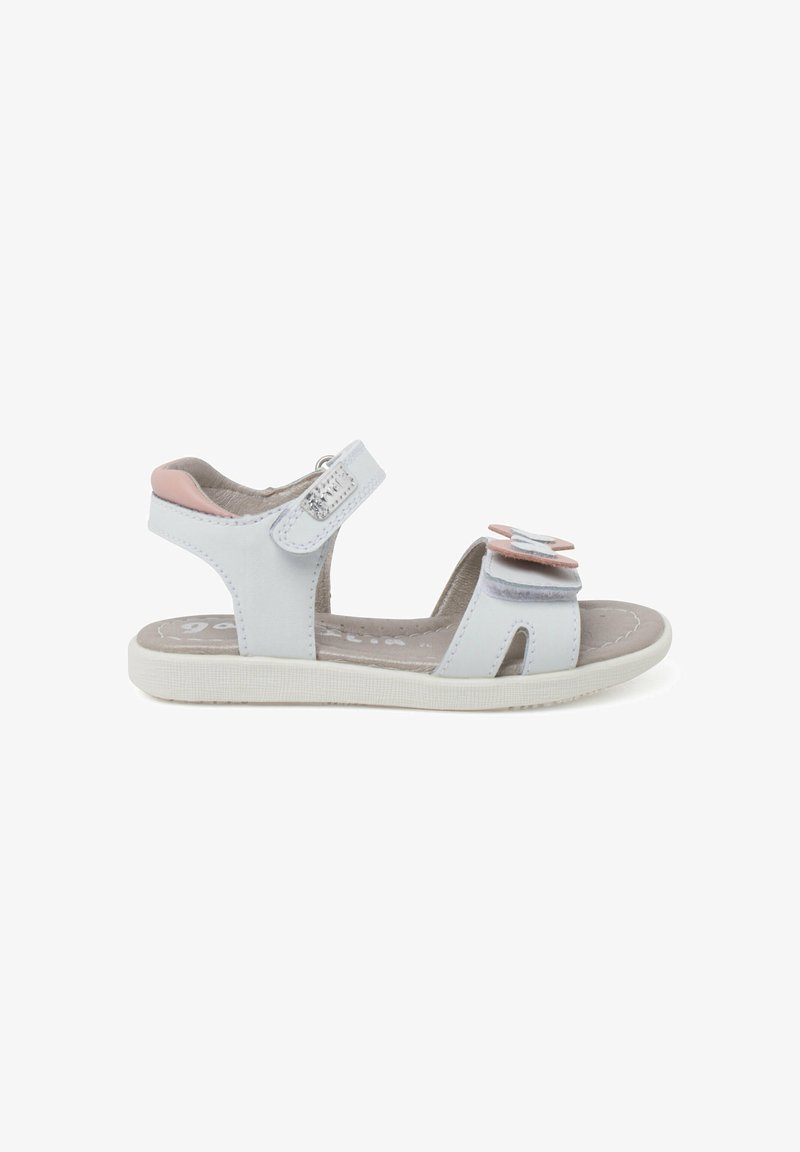 White sandals with pink accents, velcro straps, and layered flower details. Made of synthetic material with a textured sole for grip.