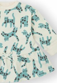 Vestido color crema claro con una falda acampanada, con un divertido estampado de gatos azules con manchas negras. Hecho de algodón suave y elástico.