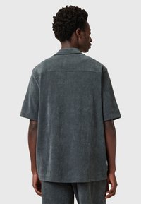 Grijze T-shirt met korte mouwen en een ontspannen pasvorm, met een zachte textuur, een eenvoudige kraag en een vlakke yoke aan de achterkant. Casual ontwerp met minimale details.