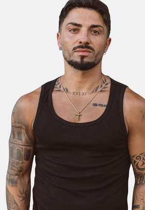 Schwarzes, geripptes Tanktop an einer Person mit Tätowierungen. Das Tanktop hat breite Träger und einen runden Ausschnitt, ergänzt durch goldenen Schmuck.