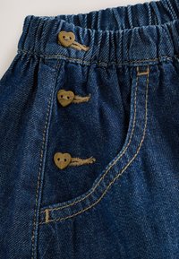 Jeansshorts in dunkelblau mit strukturierter Oberfläche, elastischem Bund und drei hellbraunen, herzförmigen Holzknöpfen.