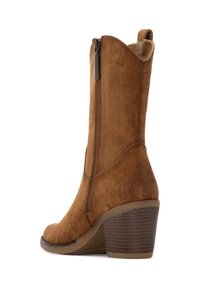 Stivale alla caviglia in suede marrone con zip laterale, punta rotonda e tacco a blocco. Presenta una suola testurizzata e un design alto.