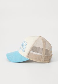 Tan and light blue trucker cap; mesh back, structured front. Features embroidered text and curved brim with contrasting stitching details.