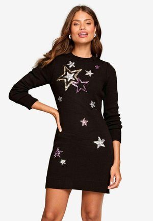 Vestito a maglia nero con maniche lunghe, caratterizzato da decorazioni a forma di stella in paillettes multicolori argento, oro e viola su uno sfondo testurizzato.