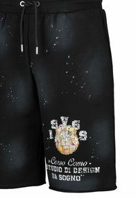 Zwarte shorts van zachte stof met een tailleband met trekkoord. Heeft een kleurrafische leeuw en witte tekst, met spetterdetails door het hele ontwerp.