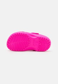 Sole di scarpa in gomma di colore rosa brillante con un motivo di grip testurizzato, caratterizzato da piccole scanalature e indentazioni circolari per trazione e stabilità.
