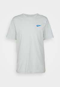 Light green, short-sleeve cotton T-shirt with a round neck and blue Nike logo on the left chest. Smooth texture and standard fit.