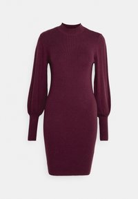 Abito a coste color bordeaux con collo alto, lunghe maniche a sbuffo e silhouette aderente, che arriva a metà coscia.