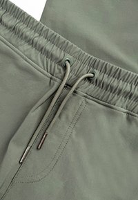 Lichtgroene joggers met een elastische tailleband en trekkoord. Beschikt over een gladde stoftextuur en subtiele stikdetails.