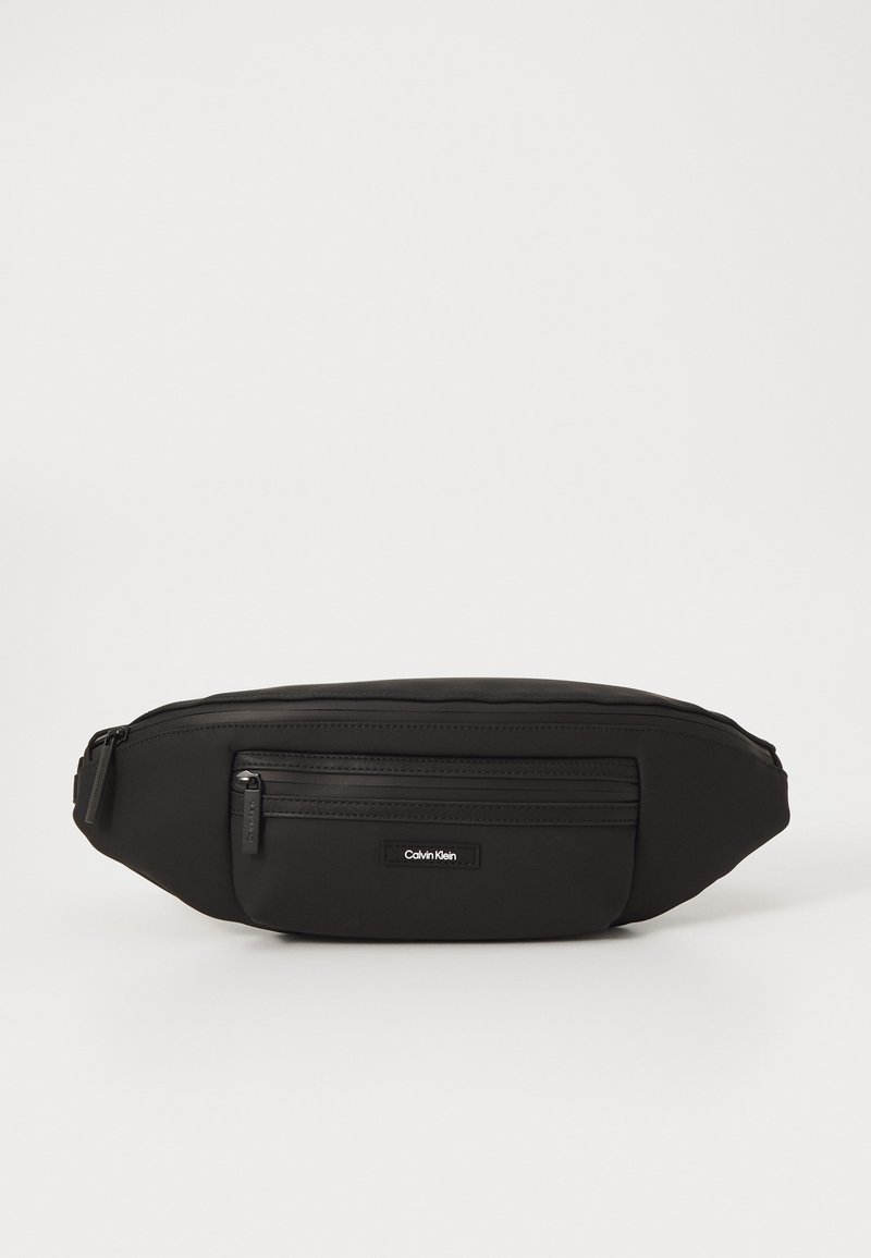 Rucsac fanny din nailon negru cu un design elegant, având un buzunar frontal cu fermoar, un patch cu logo și o textură netedă.