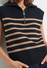 Marinblå ärmlös tröja med kvartslång dragkedja, med horisontella beiga ränder, ribbad struktur och avslappnad passform.