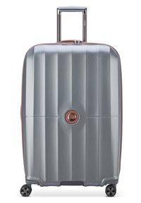 Valigia rigida di colore argento con superficie testurizzata, dettagli marroni a contrasto, manico telescopico e quattro ruote nere.