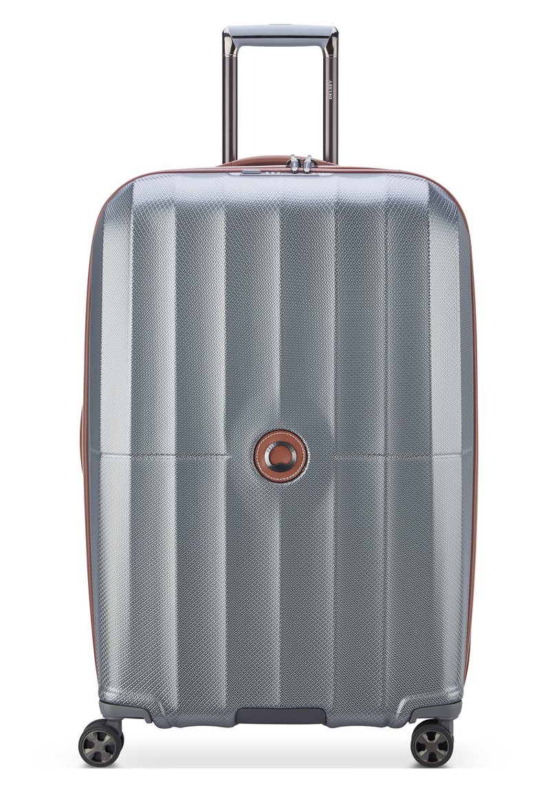 Valigia rigida di colore argento con superficie testurizzata, dettagli marroni a contrasto, manico telescopico e quattro ruote nere.