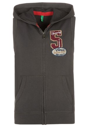 Sudadera sin mangas con cremallera en gris oscuro, con bolsillos delanteros y parches bordados que dicen "Upcoming S Tour" y "Vintage And Used LP".