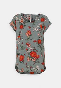 Blusa de manga corta floral en tejido verde apagado, con flores en tonos rojo, rosa y blanco, con una ligera curvatura en el dobladillo y detalle de agujero en la parte posterior.
