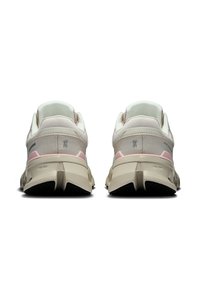 Bézs színű sportcipők rózsaszín részletekkel, hálós és szintetikus anyagok keverékéből készült. Kerek forma, texturált talp és megerősített sarok jellemzi.