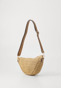 Tkaná slámová taška na rameno ve tvaru oblouku s hnědým nastavitelním popruhem a zlatými kovovými akcenty. Texturovaný povrch s přírodním vzhledem.