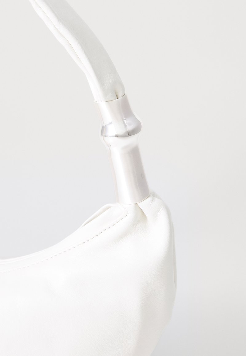 White leather handbag handle attached with a silver metallic bamboo-shaped connector against a plain light background.