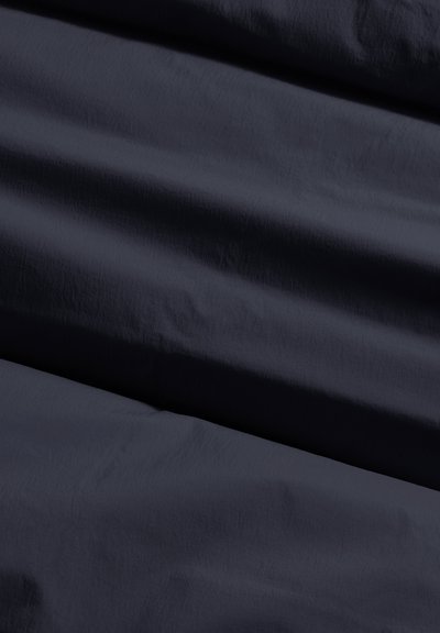 Marineblaue Stoff mit glatter Textur, der subtile Falten und ein mattes Finish aufweist. Das Material ist leicht und flexibel.