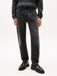 Jean droit gris foncé avec une texture délavée, design à cinq poches et passants de ceinture, associés à des chaussures noires à lacets.