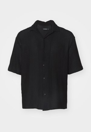 Czarna koszula z krótkim rękawem o teksturowanym, ażurowym wzorze, z kołnierzykiem i zapięciem na guziki. Lekki materiał o luźnym kroju.