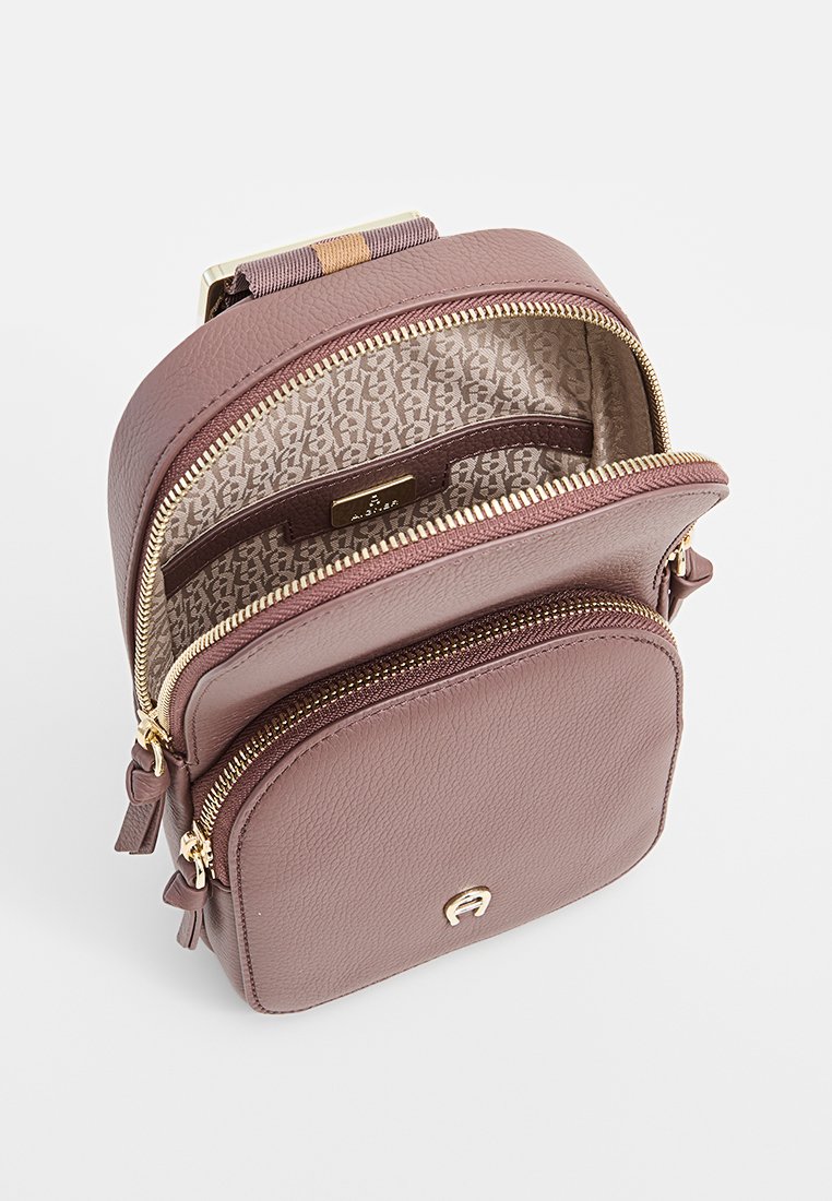Kleine mauve Crossbody-Tasche aus strukturiertem Leder, mit goldenen Reißverschlüssen, zwei Fächern und einem gemusterten Stoffinnenraum.