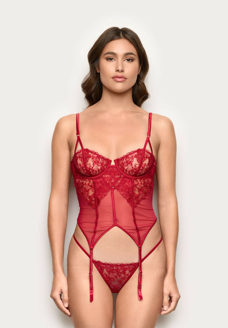Bodysuit en dentelle rouge et maille transparente avec bretelles réglables, motifs floraux et design ajusté mettant en valeur la taille et les hanches.