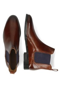 Botas Chelsea de cuero marrón con paneles laterales elásticos en azul marino y una lengüeta, que presentan una punta redondeada y una suela plana de goma negra.
