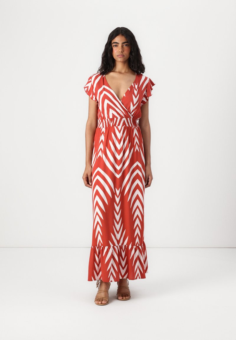 Maxime dress in orange with white chevron pattern, featuring short ruffled sleeves and an elastic waist. Flared hem with ruffle detail.