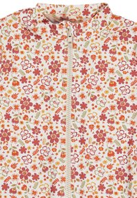Blumen-Mantel mit Reißverschluss, der auf einem cremefarbenen Hintergrund mit lebhaften roten, orangen und grünen Blumen verziert ist. Glattes Material mit einem hohen Kragen-Design.