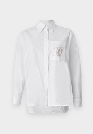 Valge puuvillane särk, millel on vasakul rinnakotis tikitud monogramm heledas pruunis. Pikad varrukad ja sirge äär.
