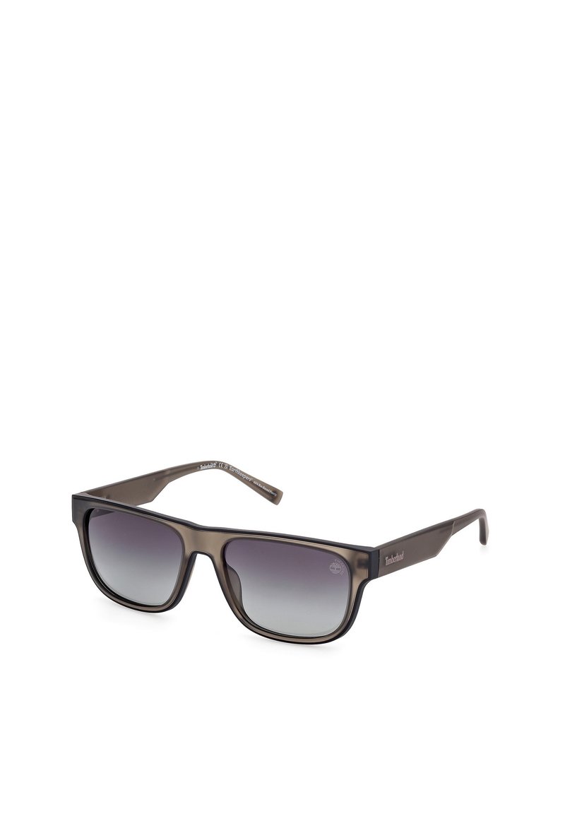 Occhiali da sole con lenti scure a gradiente e montatura in plastica marrone opaco. Forma rettangolare con un lieve marchio sulla tempia.