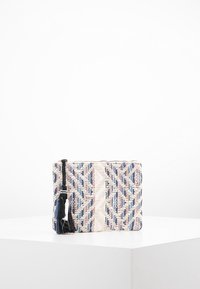 Pochette tissée en crème, bleu et rose avec un motif géométrique. Dotée d'un pompon noir sur la fermeture éclair. Forme rectangulaire, surface texturée.