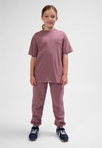 Rosa bomullst-shirt med bröstficka och matchande byxor. T-shirten har en avslappnad passform, medan byxorna har elastisk midja och muddar.