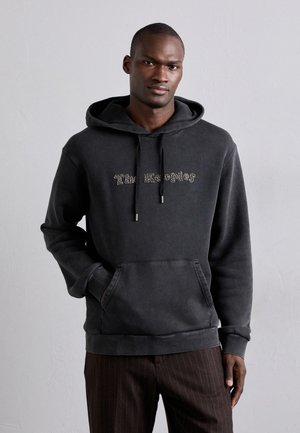 Schwarzer Hoodie mit einer Fronttasche, der ein strukturiertes Logo in kontrastierenden Farben zeigt. Der Stoff hat eine weiche, abgetragene Optik und einen lässigen Schnitt.