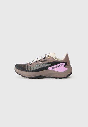 Chaussures de course avec une tige en maille noire et taupe, dotées d'accents réfléchissants, d'un logo rose et d'une semelle robuste pour une meilleure traction.