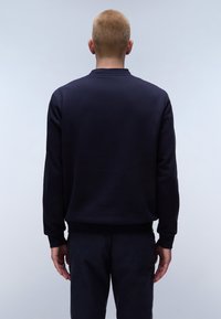 Marineblauwe sweatshirt met lange mouwen en een ronde hals. Gladde stoffen textuur en geribbelde manchetten. Eenvoudig, minimalistisch ontwerp zonder zichtbare logo's.