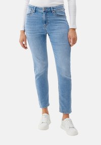 Ljust blå denimjeans med en slim passform, som har fem fickor, midjeband med bältesloopar och en rak bendesign. Kombineras med vita sneakers.