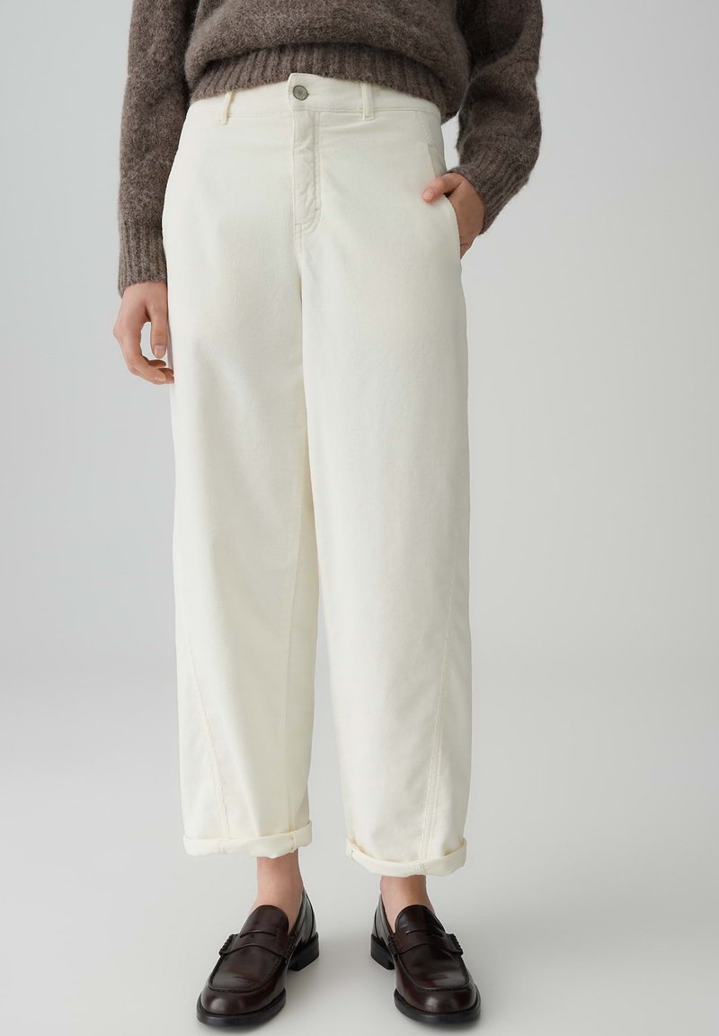 Witte denim broeken met een relaxte pasvorm, opgerolde manchetten en zijzakken. Gecombineerd met donkerbruine loafers en een gestructureerd bruin sweater.