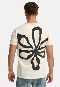 Baumwoll-T-Shirt in Creme mit einem großen schwarzen Blumendesign auf dem Rücken. Rundhalsausschnitt, kurze Ärmel und normale Passform.