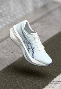 Chaussure de sport bleu clair avec tige en mesh, accents blancs et détails bleus sur le côté. Dotée de lacets ronds et d'une forme profilée.