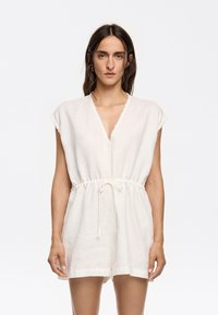 Linnen romper in gebroken wit, met een V-hals, korte mouwen, elastische tailleband met een strik, en een losse pasvorm met korte shorts.