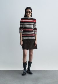 Rankomis megzta megztinis su raudonomis, rudomis ir pilkomis juostomis; derinamas su ruda zomšine sijonu. Juodi aulinukai su tekstūruotais apvadais.