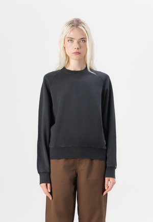 Black cotton sweatshirt with raglan sleeves, ribbed cuffs, and hem. Styled with brown wide-leg pants. Smooth texture, minimalistic design.