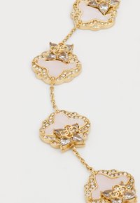 Gold-tone bracelet featuring alternating floral motifs with pink centers, rhinestone accents, and delicate chain links.
