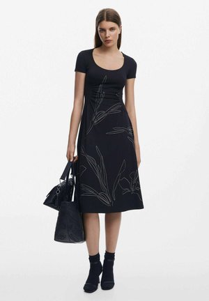 Schwarzes Kleid mit kurzen Ärmeln, das weiße florale Linienezeichnungen zeigt. Glatter Stoff mit einem taillierten Oberteil und ausgestelltem Rock.