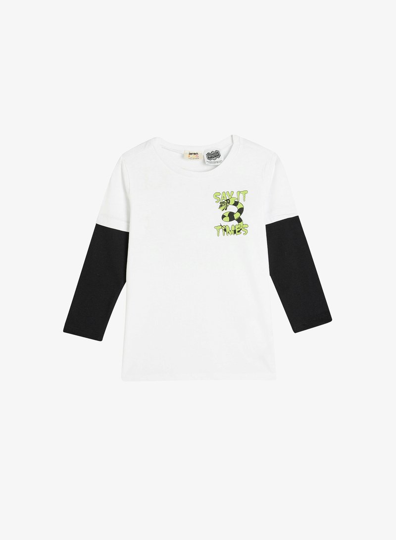 Hvid T-shirt med sorte lange ærmer, prydet med et grønt og sort grafisk design med teksten "SIG DET 3 GANGE" og et fodboldmotiv.